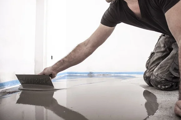 Person verteilt Estrich mit Glätter.